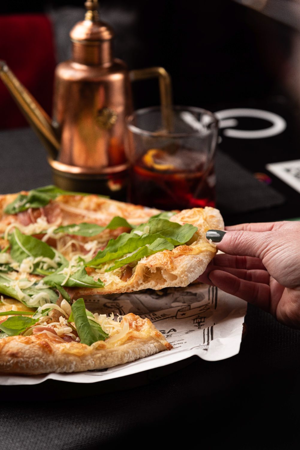 Mão servindo pizza de rúcula durante uma sessão fotográfica